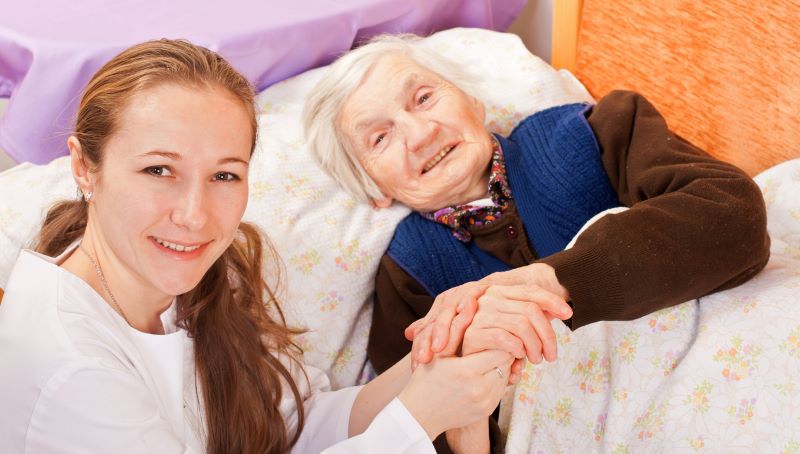 Senior person and memory care nurse holding hands